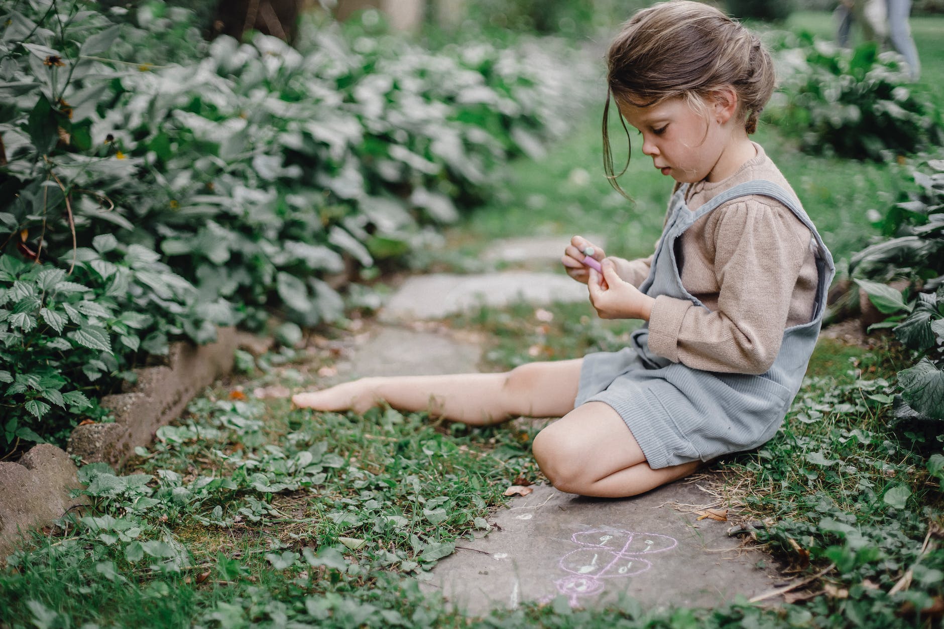 cute stylish child playing with chalks in the garden t